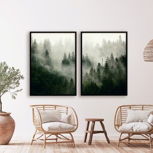 May include: Two framed prints of a misty forest scene with tall trees. The prints are hung on a white wall in a living room setting with two wicker chairs and a small wooden stool.