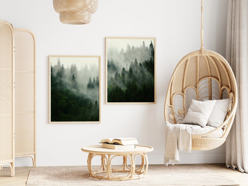 May include: Two framed prints of a misty forest scene hang on a white wall above a round wicker coffee table. A hanging wicker chair with a white cushion sits in the corner of the room.