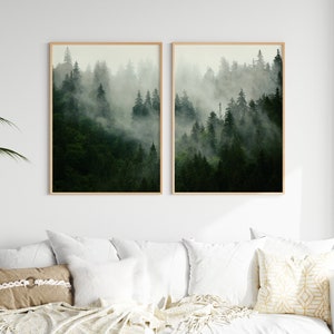 May include: Two framed prints of a misty forest scene with tall evergreen trees. The prints are in a light wood frame and are hung on a white wall.