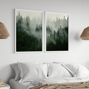 May include: Two framed prints of a misty forest scene with tall green trees. The prints are hung on a white wall above a bed with white bedding.