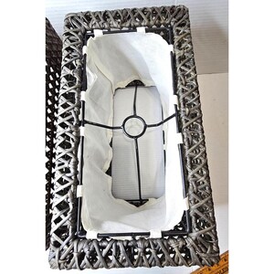 Pode incluir: Um abajur retangular de vime com um forro de tecido branco e uma moldura de metal preto. O abajur é feito de vime tecido e tem uma cor castanho escuro.