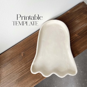 May include: Printable template for a ghost-shaped tray. The tray is white and has a smooth, slightly textured surface. The template is perfect for crafting and DIY projects.