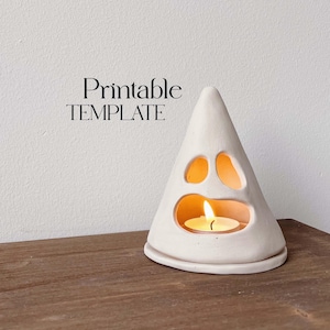 Puede incluir: Portavelas de cerámica blanca en forma de fantasma con una cara recortada y una vela pequeña en su interior. El texto "Printable TEMPLATE" está por encima del fantasma.