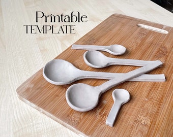 May include: A collection of handmade, light gray clay spoons of varying sizes arranged on a wooden cutting board. The text "Printable TEMPLATE" is displayed in a serif font.