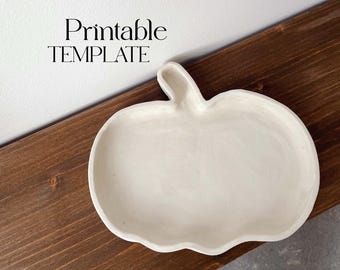 May include: A white ceramic pumpkin-shaped dish. The dish is on a wooden surface. Printable TEMPLATE is written above the dish.