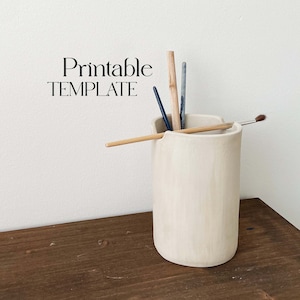 Puede incluir: Un porta lápices de cerámica blanca con un borde superior ondulado. El porta lápices está lleno de varios pinceles y lápices. El texto "Printable TEMPLATE" es visible en la esquina superior izquierda de la imagen.