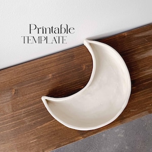 Puede incluir: Un plato de cerámica blanco en forma de media luna sobre una superficie de madera marrón. El texto "Printable TEMPLATE" es visible sobre el plato.