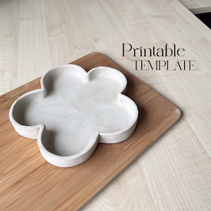 May include: A white concrete flower-shaped dish on a wooden cutting board. The text "Printable TEMPLATE" is visible above the dish.