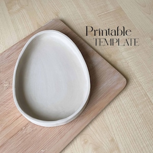 May include: A white ceramic oval tray on a wooden surface. The tray is a printable template.