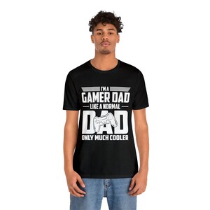 May include: A black t-shirt with white text that reads "I'm a Gamer Dad - Like a Normal Dad Only Much Cooler" and a white graphic of a video game controller.