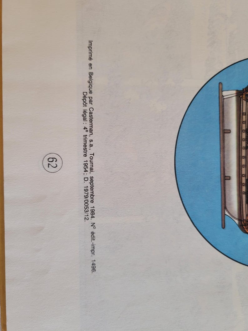 May include: A blue and white illustration of a ship with a white hull and a blue sail. The ship is surrounded by a blue circle. The text "Imprim&eacute; en Belgique par Casterman, s.a., Tournai, septembre 1984. N&deg; &eacute;dit.-impr. 1496. D&eacute;p&ocirc;t l&eacute;gal: 4&ordm; trimestre 1954; D. 1979/0053/12." is printed below the image.