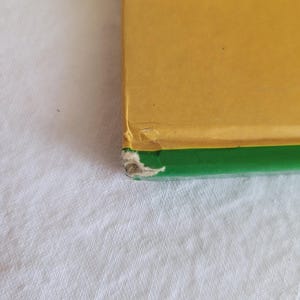 May include: A book with a yellow cover and a green spine. The book is slightly worn.