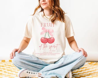 May include: A white t-shirt with a pink cherry graphic and the text "FRUIT of the spirit GAL 5:22-23 LOVE, JOY, PEACE, PATIENCE, KINDNESS, GOODNESS, FAITHFULNESS, GENTLENESS & SELF CONTROL"