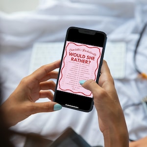 May include: A person is holding a smartphone displaying a pink and red "Would She Rather?" game for a hen party. The game is titled "Charlotte's Bachelorette Would She Rather?" and features a list of questions.