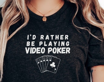 May include: A dark grey t-shirt with the text "I'd rather be playing video poker" and a graphic of playing cards.