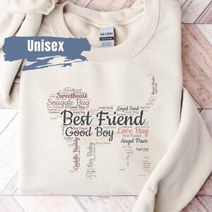 May include: A beige unisex sweatshirt with a word cloud design featuring the words "Best Friend", "Good Boy", "Love Bug", "Angel Paws", "Cuddle Buddy", "Sweetheart", "Snuggle Bug", and "Loyal Soul".
