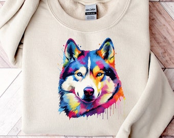 May include: A beige sweatshirt with a colorful watercolor illustration of a husky dog's face. The sweatshirt has a Gildan brand tag.
