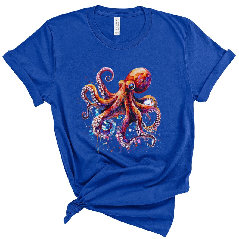 Puede incluir: Una camiseta azul real con un dise&ntilde;o de pulpo acuarela colorido. El pulpo es rojo, naranja y morado con manchas blancas. El dise&ntilde;o tiene salpicaduras de color alrededor del pulpo.