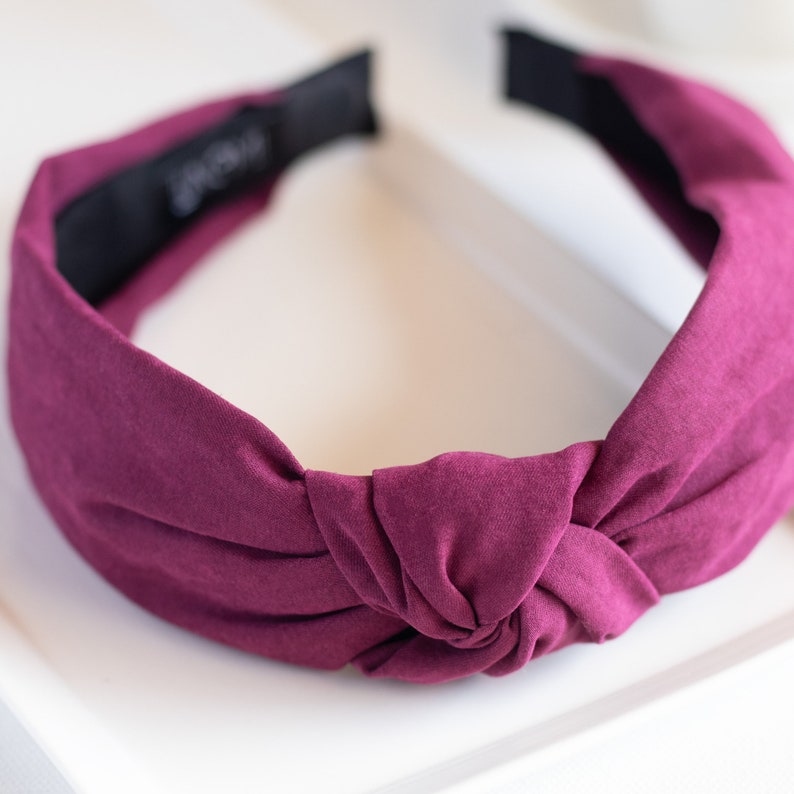 A close-up of one top knot headband featuring a top knot detail in the color purple.