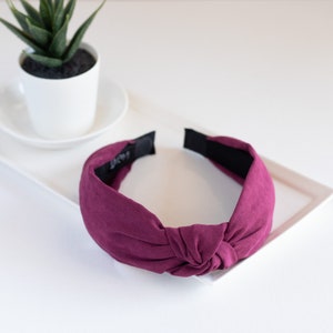 One headband featuring a top knot detail in the color purple.