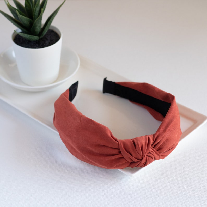 One orange headband featuring a top knot detail.