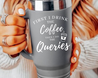 May include: A matte gray stainless steel tumbler with a handle, a clear lid, and a straw. The tumbler features white text that reads: FIRST I DRINK THE Coffee THEN I DO THE Queries, accompanied by a small graphic of a coffee cup with a heart.