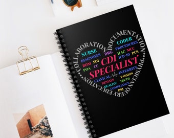 May include: A black spiral-bound notebook with the words "CDI Specialist" in a heart-shaped design. The design includes medical terms like "Nurse," "Diagnoses," and "Procedures." The notebook is on a white surface with sunglasses and a paper clip.