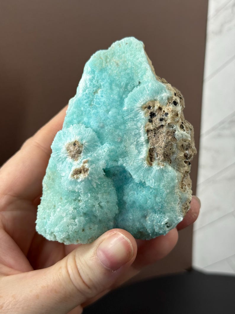 Puede incluir: Un vibrante esp&eacute;cimen mineral en bruto con un llamativo tono turquesa. La piedra presenta una superficie texturizada con formaciones cristalinas e inclusiones marrones y negras. Esta pieza &uacute;nica es una gema natural sin pulir.