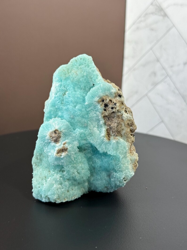 Puede incluir: Impresionante esp&eacute;cimen mineral natural con una vibrante estructura cristalina azul claro. El mineral tiene una superficie rugosa y texturizada con &aacute;reas de color marr&oacute;n y beige. La forma general es irregular y org&aacute;nica, mostrando la belleza de las formaciones naturales.