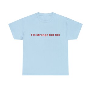 May include: A light blue t-shirt with the text "I'm strange but hot" printed in red.