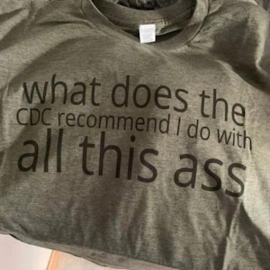 May include: A gray t-shirt with the text "what does the CDC recommend I do with all this ass" printed in black. The shirt is folded and appears to be made of a soft material.