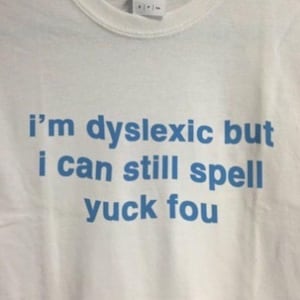 May include: White t-shirt with blue text that reads "i'm dyslexic but i can still spell yuck fou"