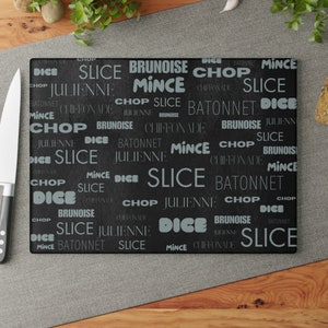 May include: Black cutting board with white text listing different knife cutting techniques, including dice, julienne, mince, chop, brunoise, and chiffonade.