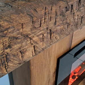 Puede incluir: Una chimenea de madera r&uacute;stica con una chimenea el&eacute;ctrica incorporada. La chimenea tiene un marco negro y un frente de vidrio con brasas rojas incandescentes.