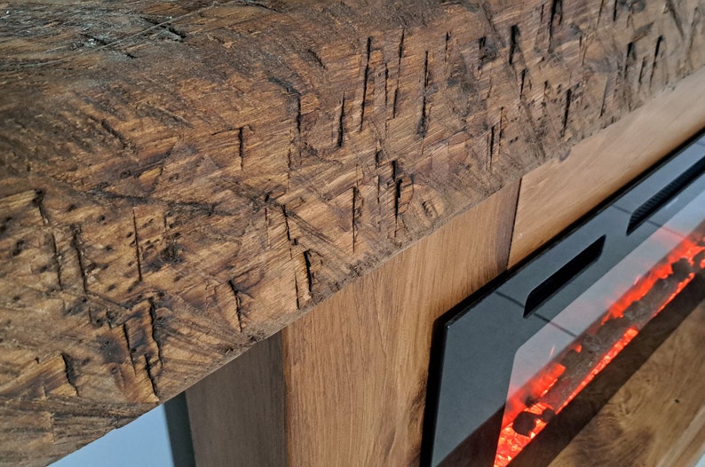 Puede incluir: Una chimenea de madera r&uacute;stica con una chimenea el&eacute;ctrica incorporada. La chimenea tiene un marco negro y un frente de vidrio con brasas rojas incandescentes.