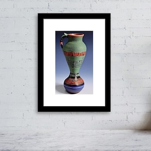 Può includere: Un vaso in ceramica verde con motivi geometrici rossi e neri e una base blu. Il vaso ha un manico ed è decorato con geroglifici.