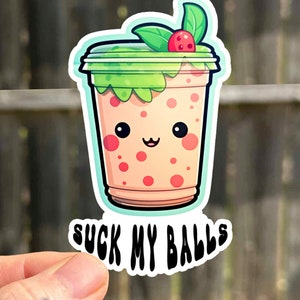 Puede incluir: Una pegatina con un vaso de té de burbujas de dibujos animados con una tapa verde, una cereza roja y una cara linda. El texto "SUCK MY BALLS" está impreso debajo del vaso.