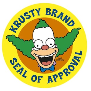 Op de afbeelding: Een gele cirkel met de tekst "Krusty Brand Seal of Approval" in blauw en wit. Een cartoonclown met groen haar en een rode neus bevindt zich in het midden van de cirkel.
