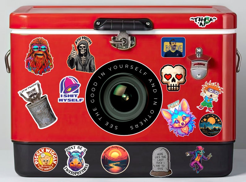 Puede incluir: Una nevera roja de metal con varias pegatinas. Las pegatinas presentan una variedad de dise&ntilde;os, incluyendo un esqueleto, un mapache, una lente de c&aacute;mara, una calavera, un zorro, una puesta de sol y una l&aacute;pida. El texto en las pegatinas incluye "Stay Positive", "I Shit Myself", "See the Good in Yourself and in Others", "Believe", "Foxy", "Forever Chasing Sunsets", y "Here Lies the Last Fuck I Had to Give".