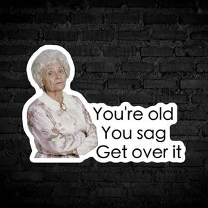 Könnte beinhalten: Ein Aufkleber mit einer Frau mit weißen Haaren und einem strengen Ausdruck. Der Text auf dem Aufkleber lautet "You're old You sag Get over it."