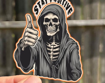 May include: A black and white sticker of a skeleton wearing a hooded robe and giving a thumbs up. The text "STAY POSITIVE" is written in a circle around the skeleton.