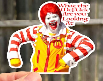 May include: A red and white striped sticker of Ronald McDonald with the text "What the McFuck Are you Looking At" in white letters.