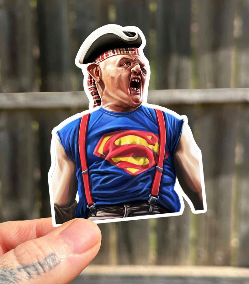 K&ouml;nnte beinhalten: Ein Aufkleber mit einer Comicfigur, die einen rot-wei&szlig;-blauen Piratenhut, ein blaues Hemd mit einem roten Superman-Logo und rote Hosentr&auml;ger tr&auml;gt. Die Figur hat einen &uuml;berraschten Ausdruck und schreit.