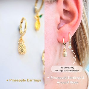 A gold pineapple earrings. The pineapple charm is three-dimensiona lookes exquisite . 14K Gold-filled materials. These hoops exude elegance and playfulness, featuring designed pineapple pendant add a touch of tropical joy to ensemble.