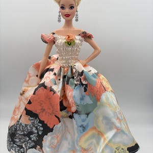 May include: A white ceramic mug with a black handle and the text "But First, Coffee" in a bold, black font. The mug is set against a neutral background, highlighting its simple design.