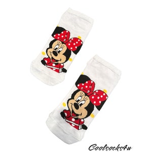 May include: A pair of white socks with a red and white polka dot bow and a cartoon image of Minnie Mouse. The socks have yellow polka dots.