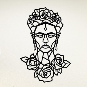 May include: Black and white geometric wall art featuring a stylised portrait of Frida Kahlo with roses around her neck. The art is mounted on a white wall in a living room setting.