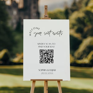 以下が含まれることがあります： 黒文字とQRコードが書かれた白い看板。テキストは「ようこそ、あなたの席はあなたを待っています。席を見つけるためにスキャンしてください。ソフィア＆エリヤ 28.02.20XX」です。