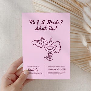 May include: A pink bridal shower invitation with the text "Me? A Bride? Shut Up!" and an illustration of a woman in a champagne glass. The invitation includes event details in dark pink text.
