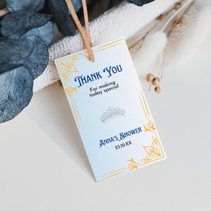 May include: A white thank you card with gold and blue accents. The card has a crown design and the text "Thank You for making today special. Anna's Shower 23.10.XX"